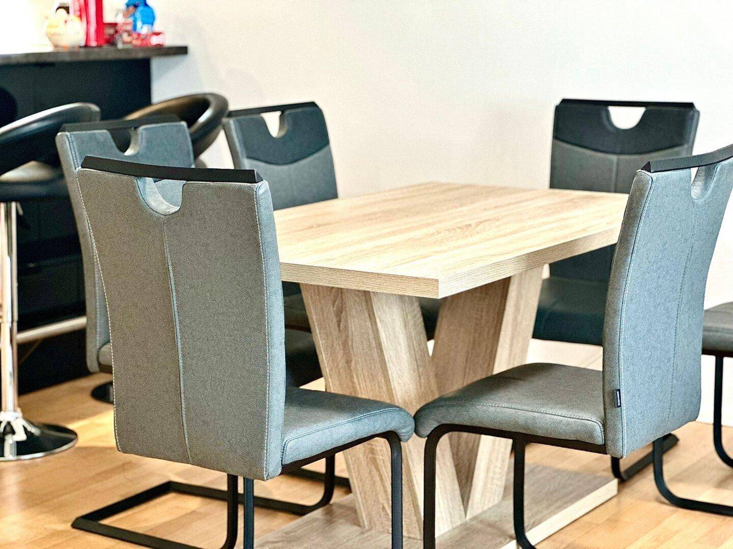 Essbereich mit modernem Holztisch und sechs grauen Stühlen, angrenzend an die Küche.