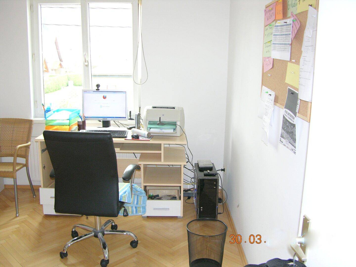 Arbeitsbereich mit Schreibtisch, Bürostuhl und Computer, gut beleuchtet durch ein großes Fenster.