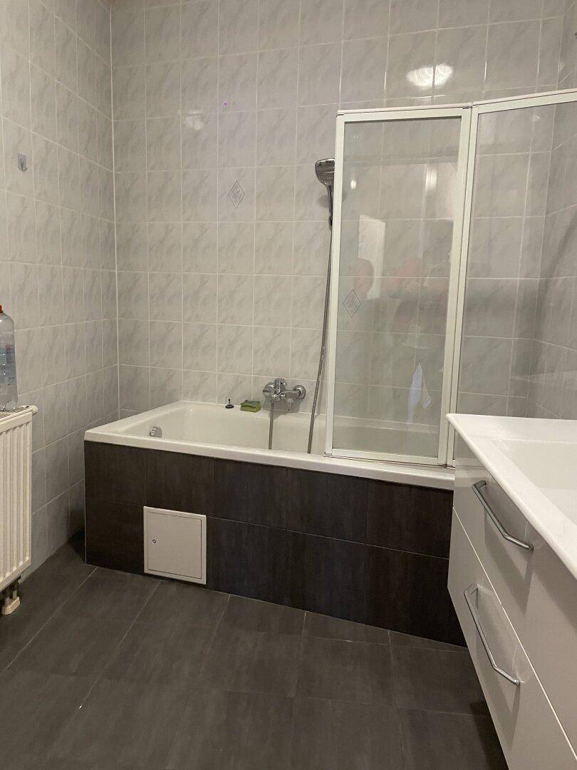 Badezimmer mit Badewanne, Duschabtrennung und einem modernen Waschtischunterschrank.