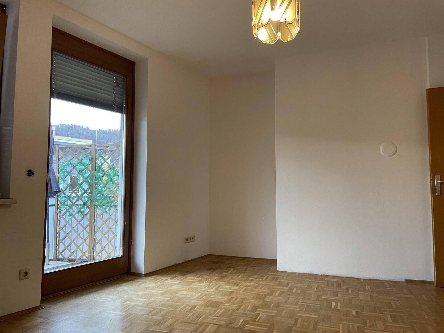 Geräumiges Zimmer mit Parkettboden und direktem Zugang zu einem Balkon.