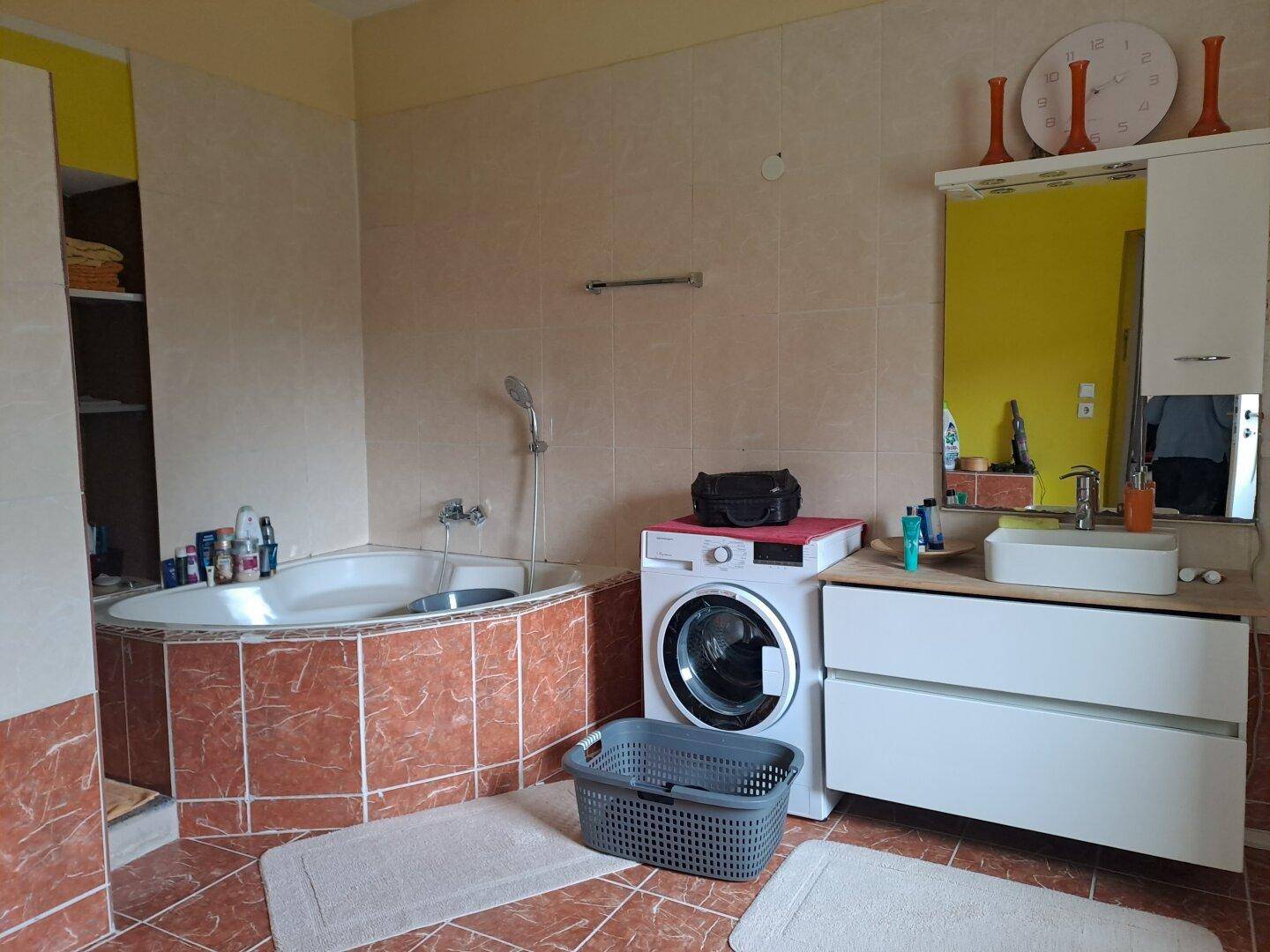 Geräumiges Badezimmer mit Eckbadewanne, Waschmaschine und modernem Waschtisch.