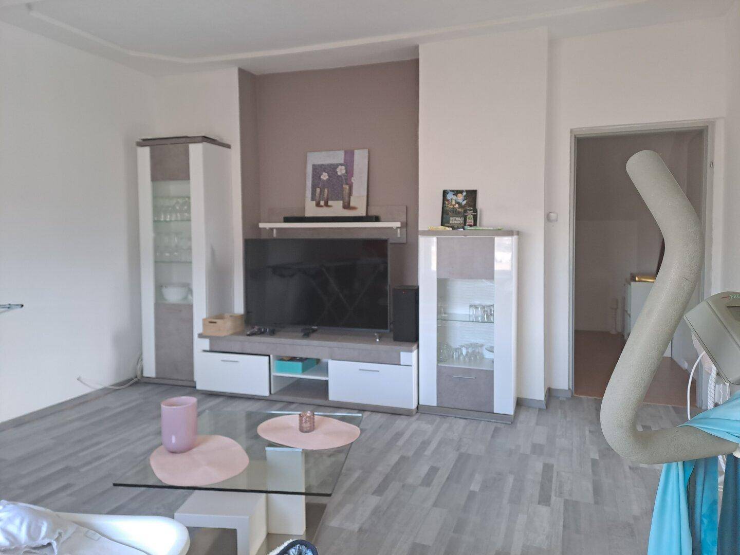Modern eingerichtetes Wohnzimmer mit TV-Möbeln, Couchtisch und hellem Boden.