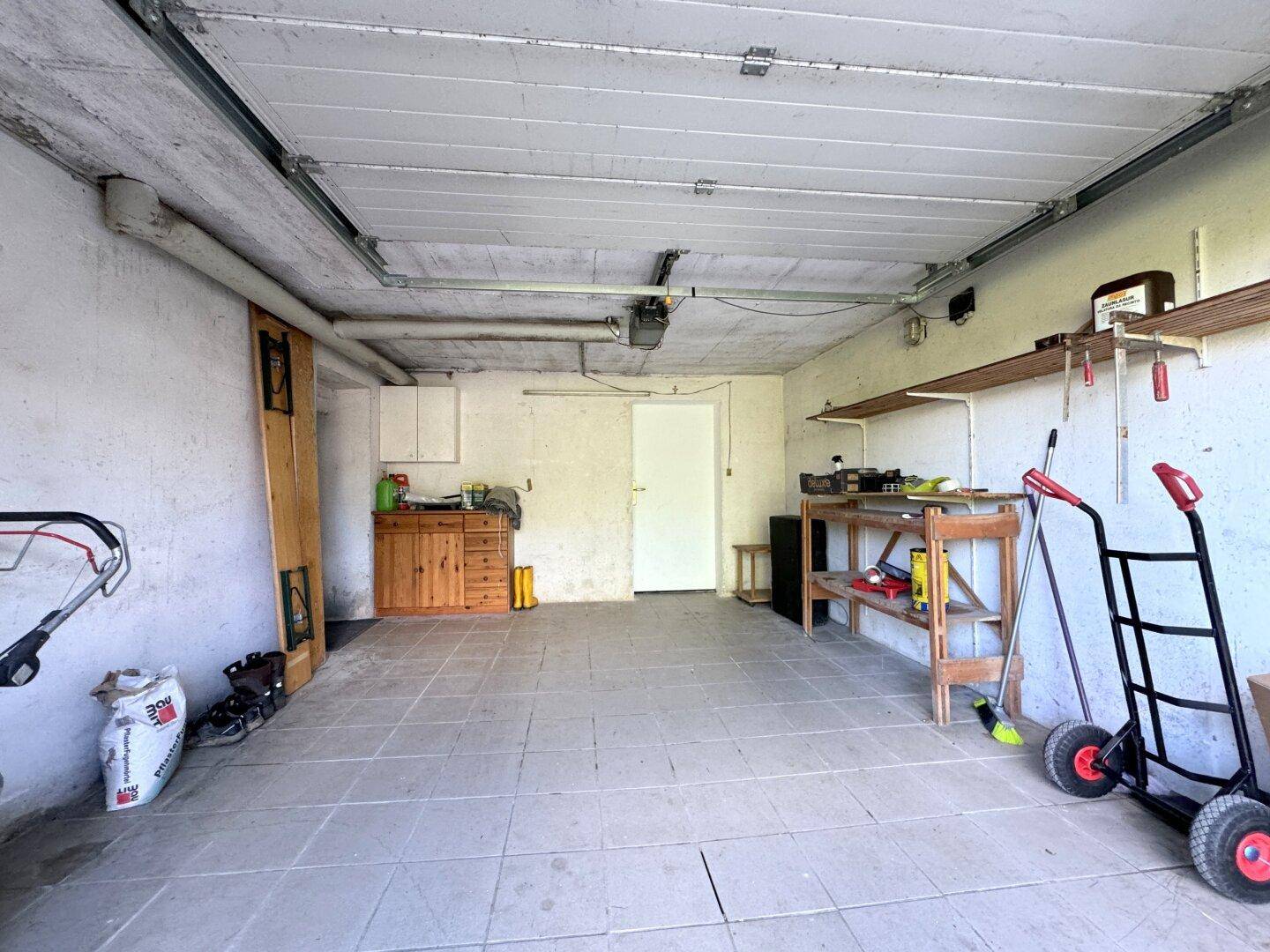 Geräumige Garage mit Werkbank, Regalen und Stauraum für Geräte.