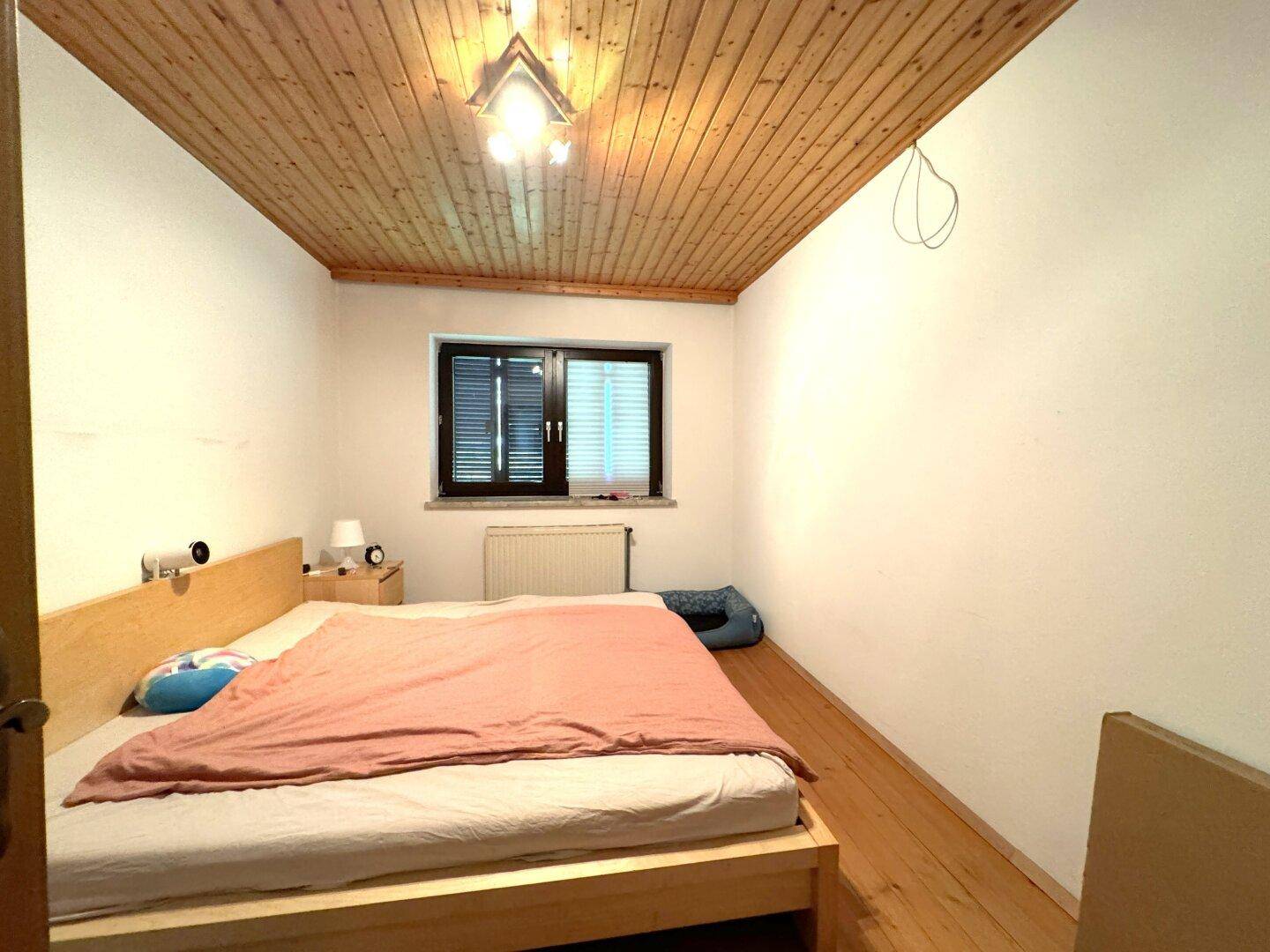 Schlafzimmer mit Holzbalkendecke, Holzboden und einem Doppelbett.