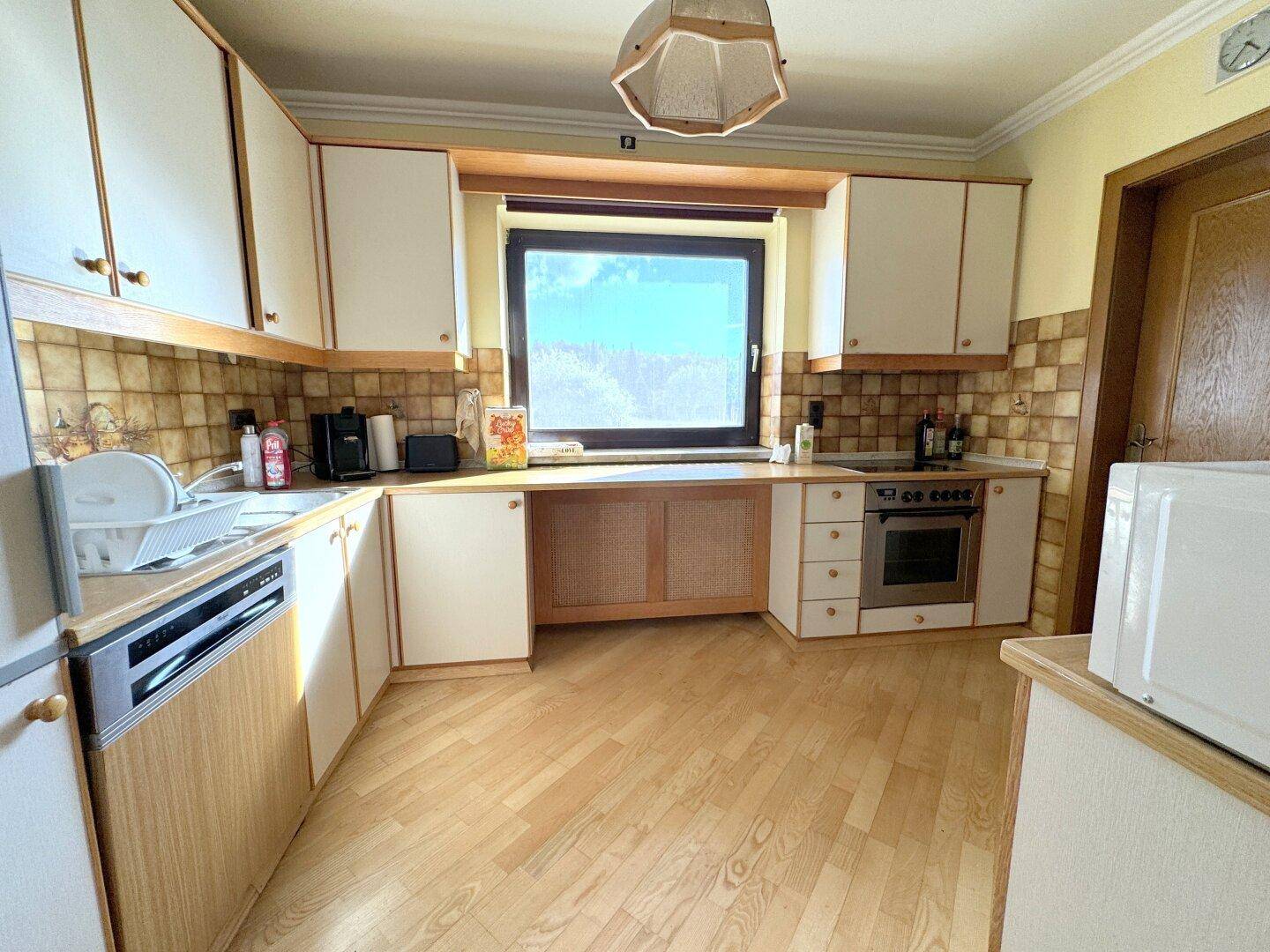 Traditionelle Küche mit hellen Schränken, Fliesenrückwand und Holzboden.