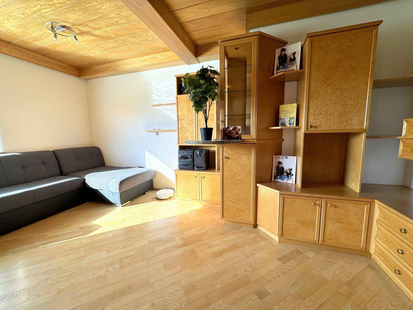 Gemütliches Wohnzimmer mit Holzbalkendecke, Parkettboden und Einbaumöbeln.