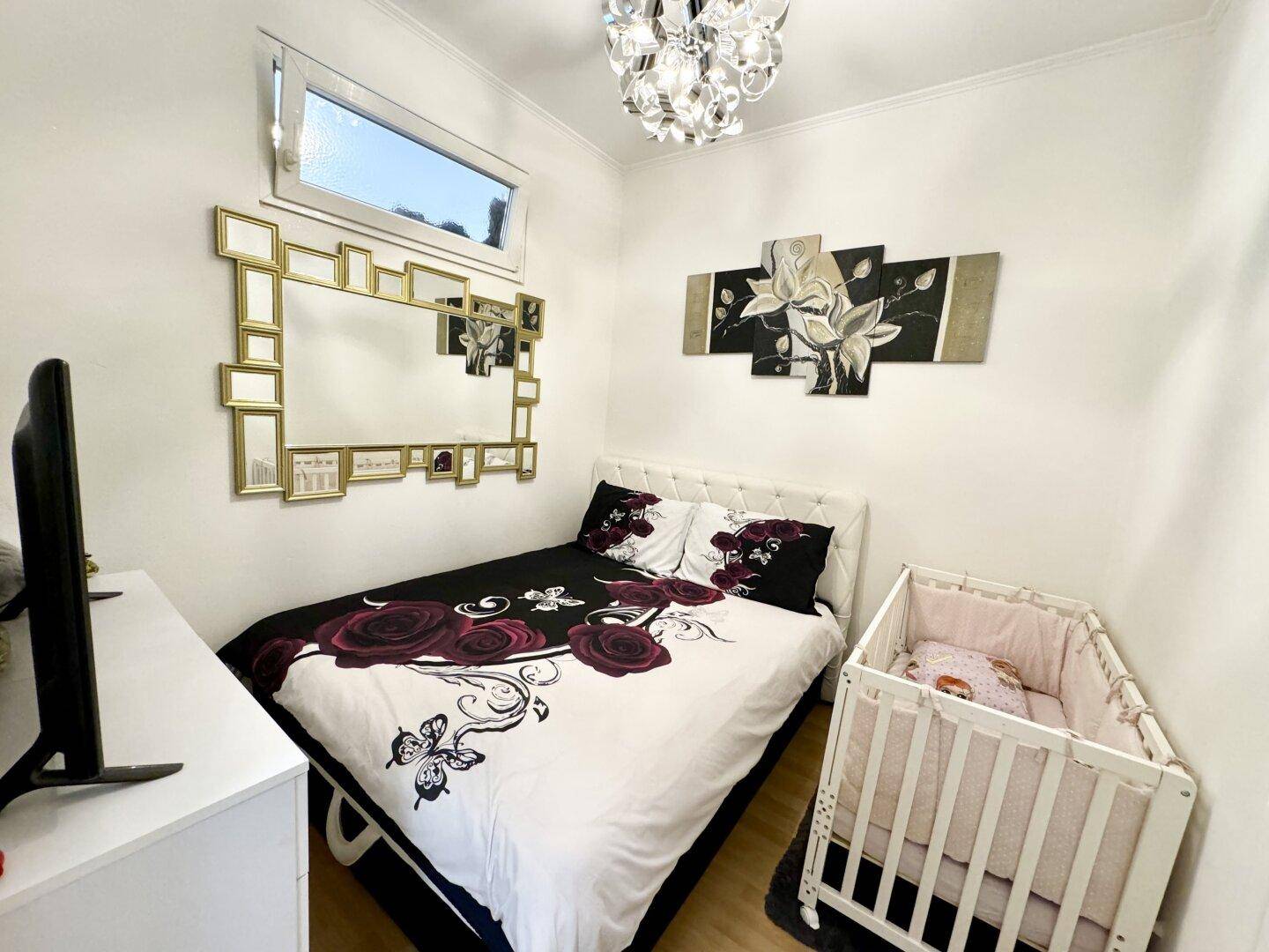 Kinderzimmer mit Einzelbett, Babybett und dekorativem Spiegel, hell und freundlich gestaltet.