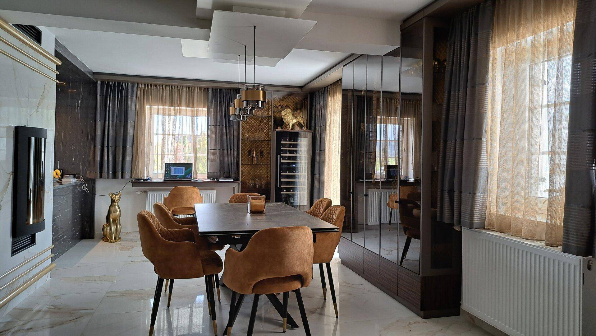 Elegantes Esszimmer mit modernem Tisch, Samtstühlen und Spiegelwänden, hell beleuchtet.