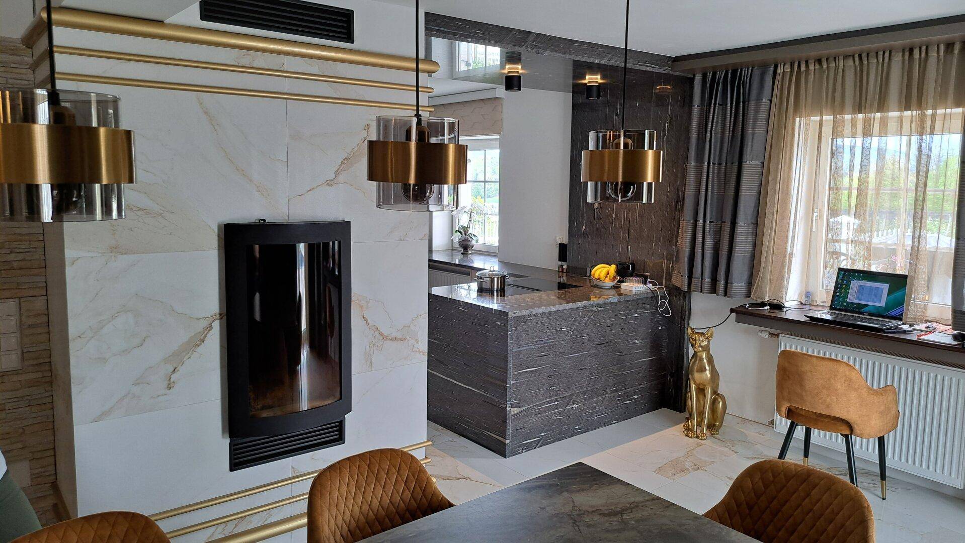 Eleganter Essbereich mit Kamin, dunklem Esstisch und goldenen Akzenten.