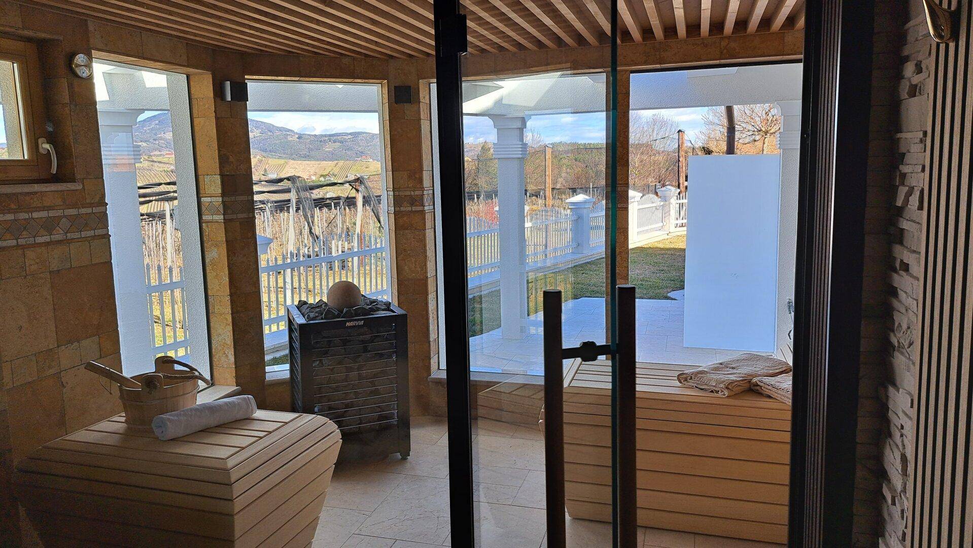 Sauna mit großen Fenstern, Holzverkleidung und Blick auf die verschneite Landschaft.