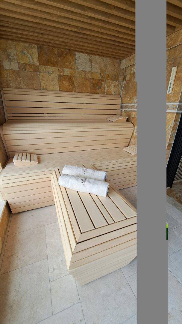 Innenansicht einer modernen Sauna mit Holzbank und Handtüchern.
