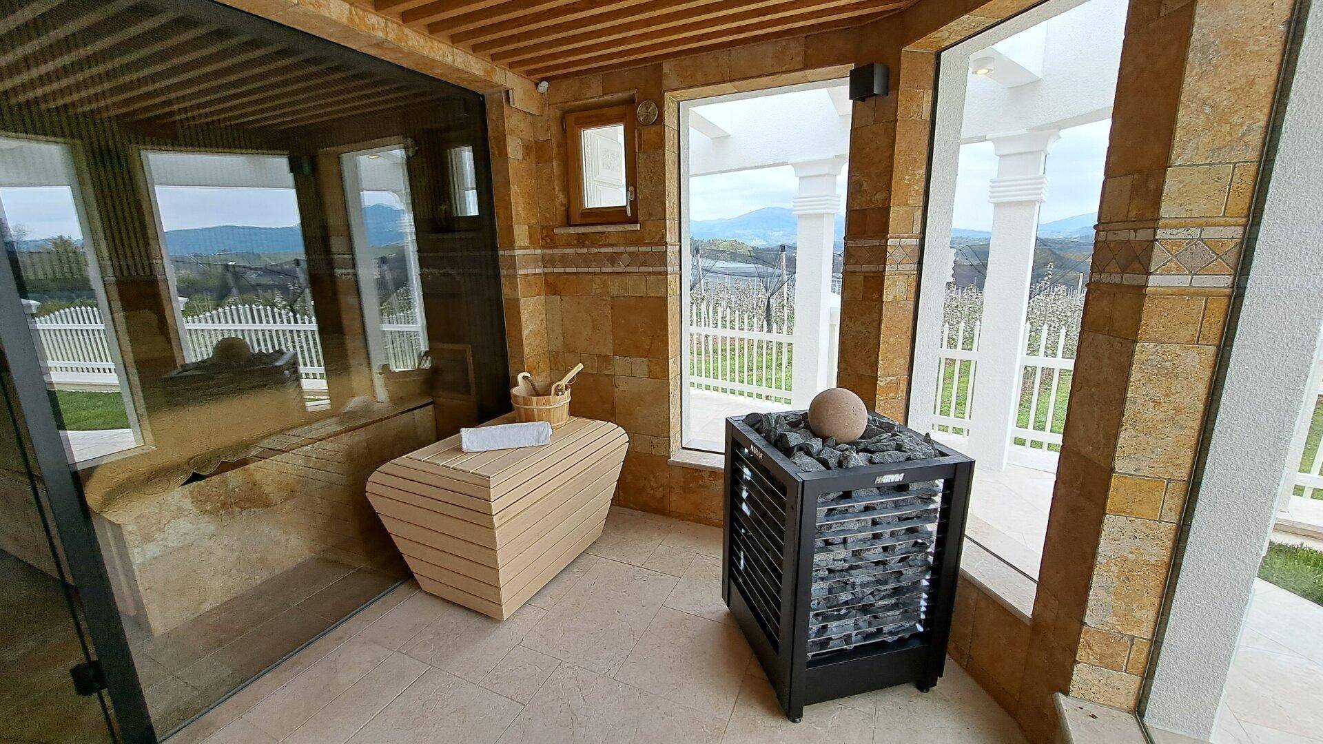 Helle Sauna mit großen Fenstern, Holzverkleidung und Blick auf die Berge.
