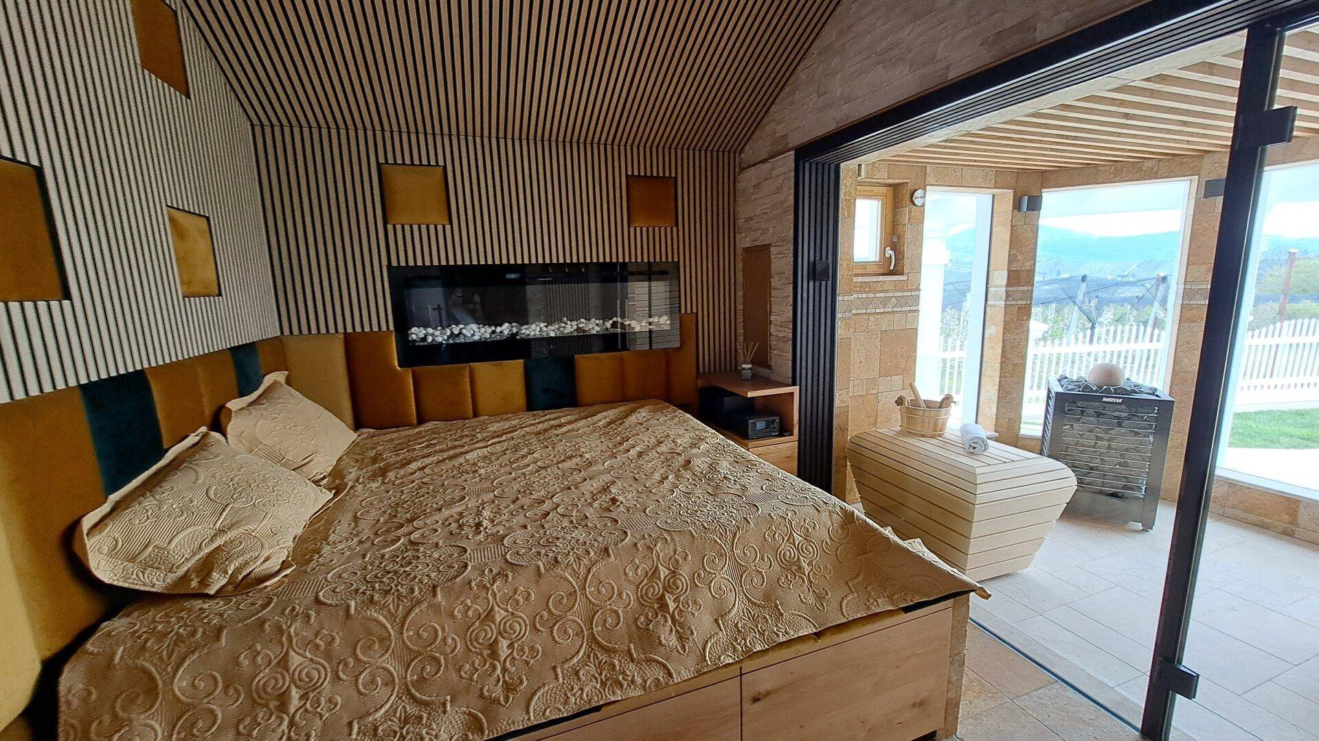 Schlafzimmer mit Holzwänden, Kamin und direktem Zugang zur Sauna.