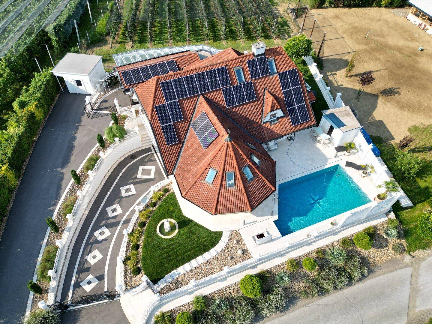 Vogelperspektive des Anwesens mit weitläufiger Auffahrt, Pool und Solaranlagen auf dem Ziegeldach.