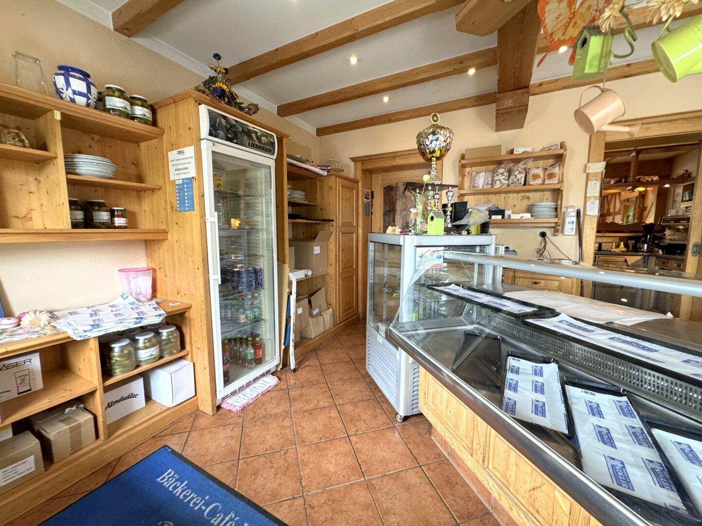 Innenansicht der Bäckerei mit Verkaufsregalen, Kühlvitrine und rustikalem Holzinterieur.