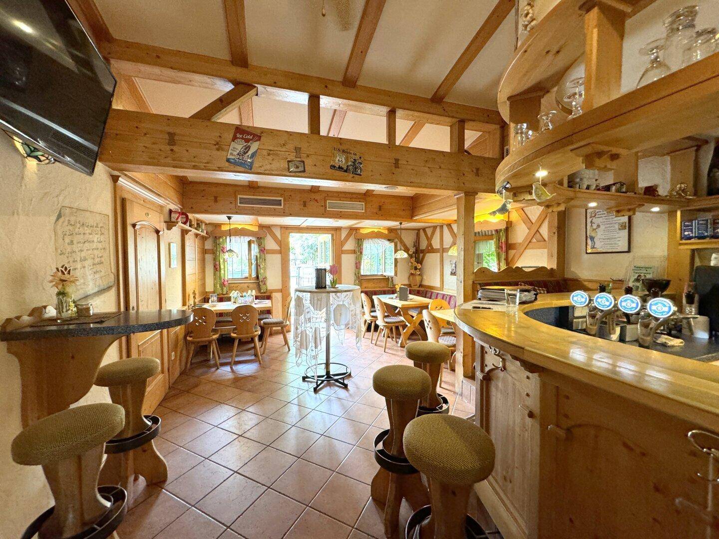 Gemütlicher Café-Bereich mit Holzbalken, rustikalen Möbeln und einer Theke.