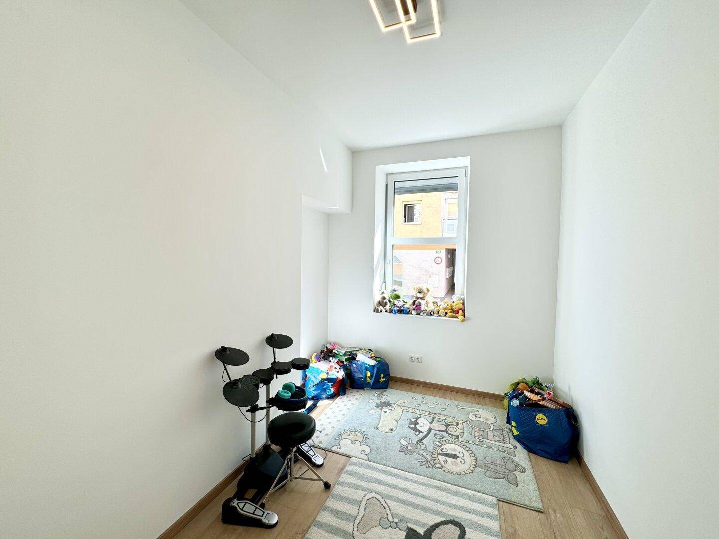 Freundliches Kinderzimmer mit Spielzeug und einem Fenster, das viel Tageslicht hereinlässt.