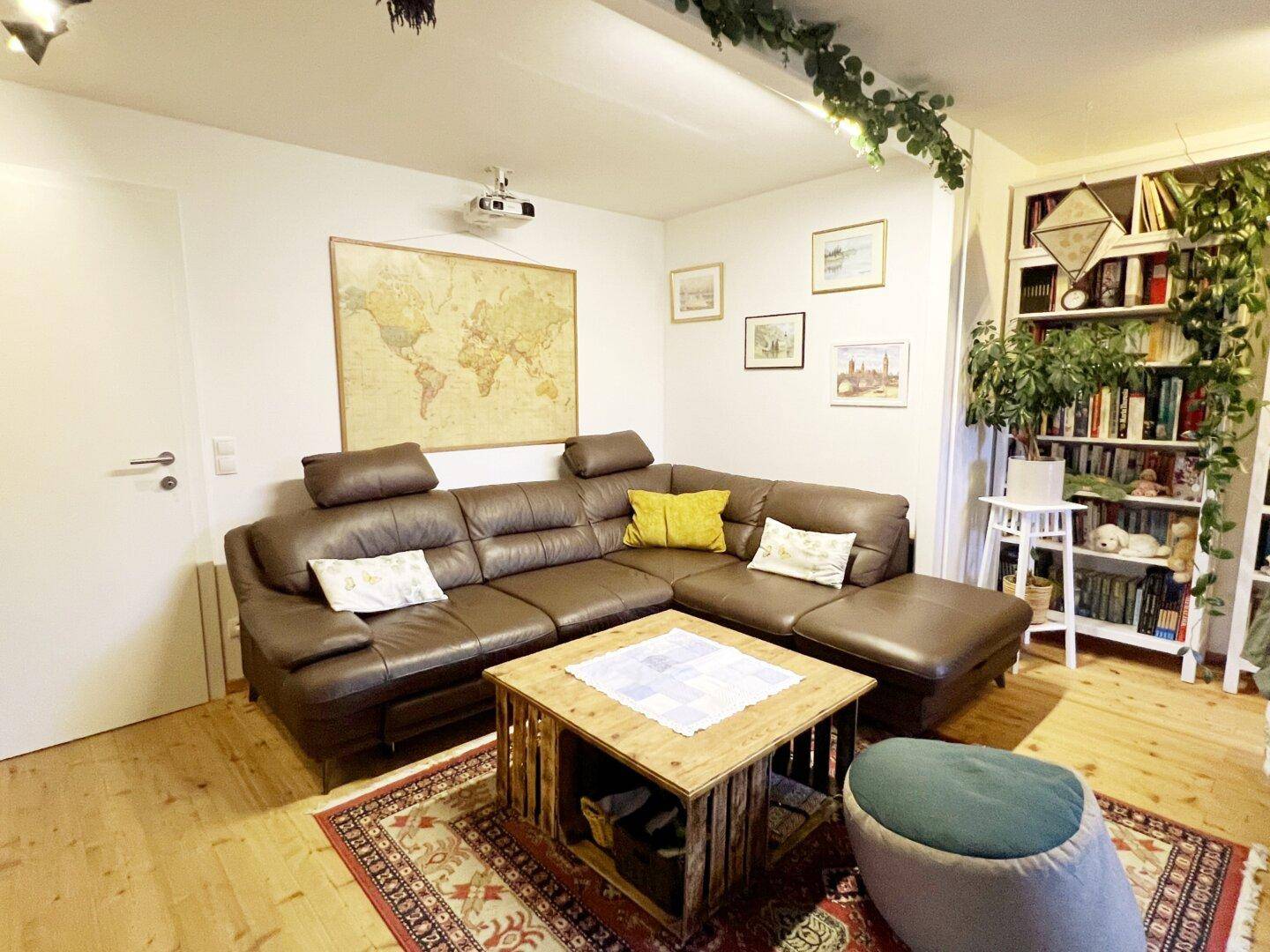 Geräumiges Wohnzimmer mit großer brauner Ledercouch, Couchtisch und Bücherregalen.