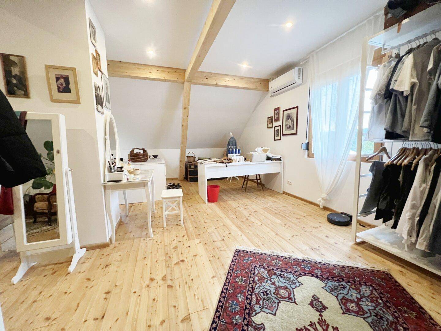 Helles Dachzimmer als Büro und Ankleidebereich genutzt, mit Holzboden und Dachschrägen.