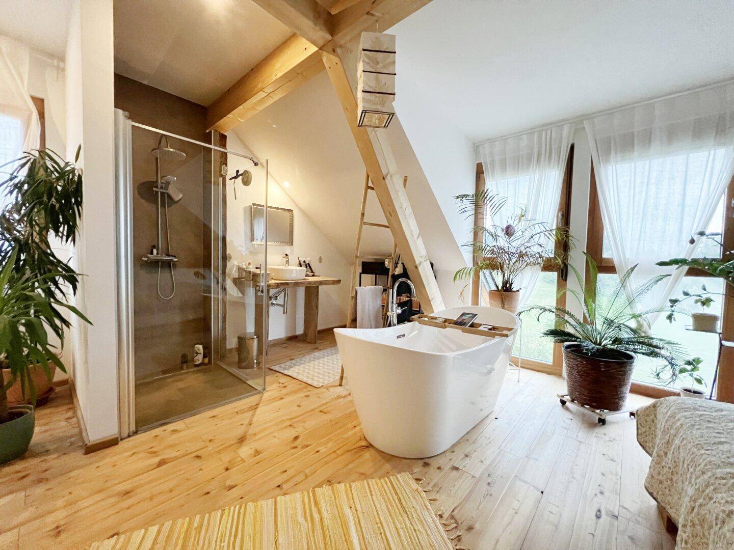 Geräumiges Dachbad mit begehbarer Dusche, freistehender Badewanne und Holzboden.