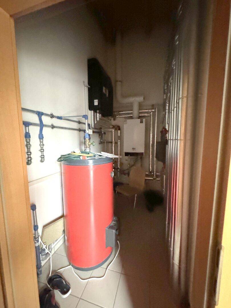 Heizungsraum mit Warmwasserspeicher und komplexen Rohrleitungen, sorgt für die Wärmeversorgung des Gebäudes.