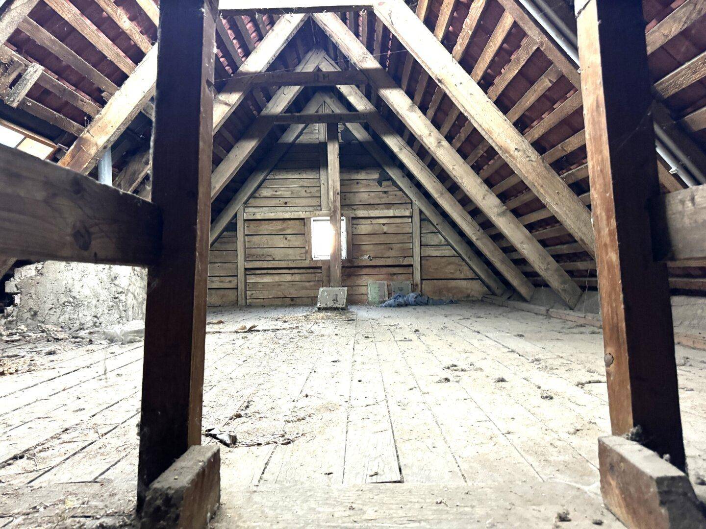 Unausgebauter Dachboden mit sichtbarer Holzkonstruktion und Holzboden.