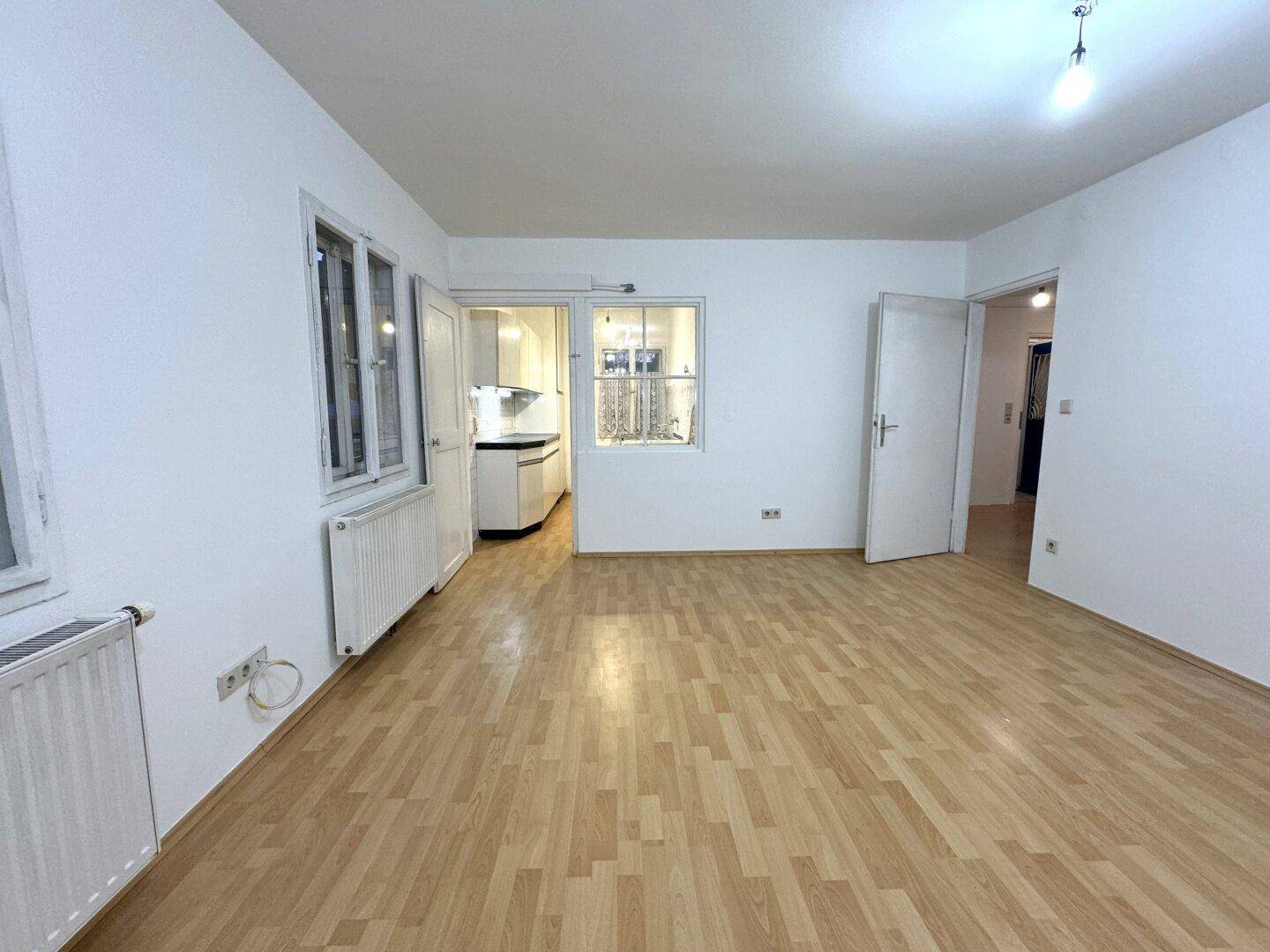 Geräumiger, heller Wohnbereich mit Laminatboden und direktem Zugang zur Küche.