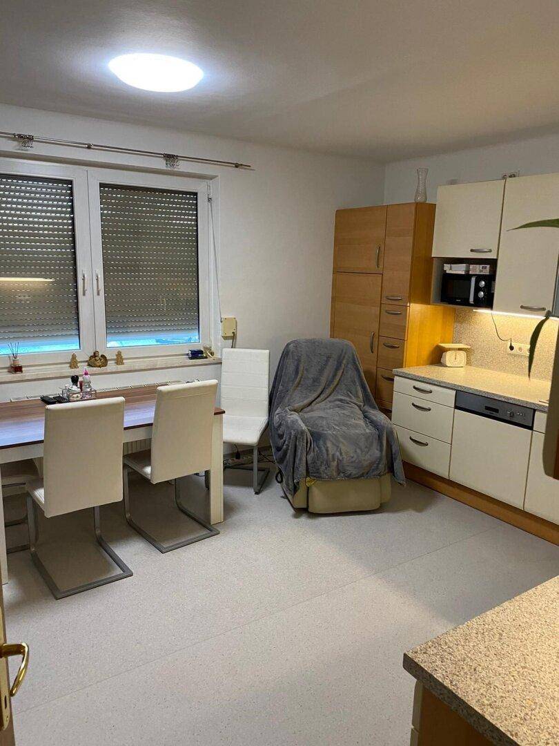 Geräumige Küche mit Essbereich, Einbauschränken und einem Fenster mit Rollläden.