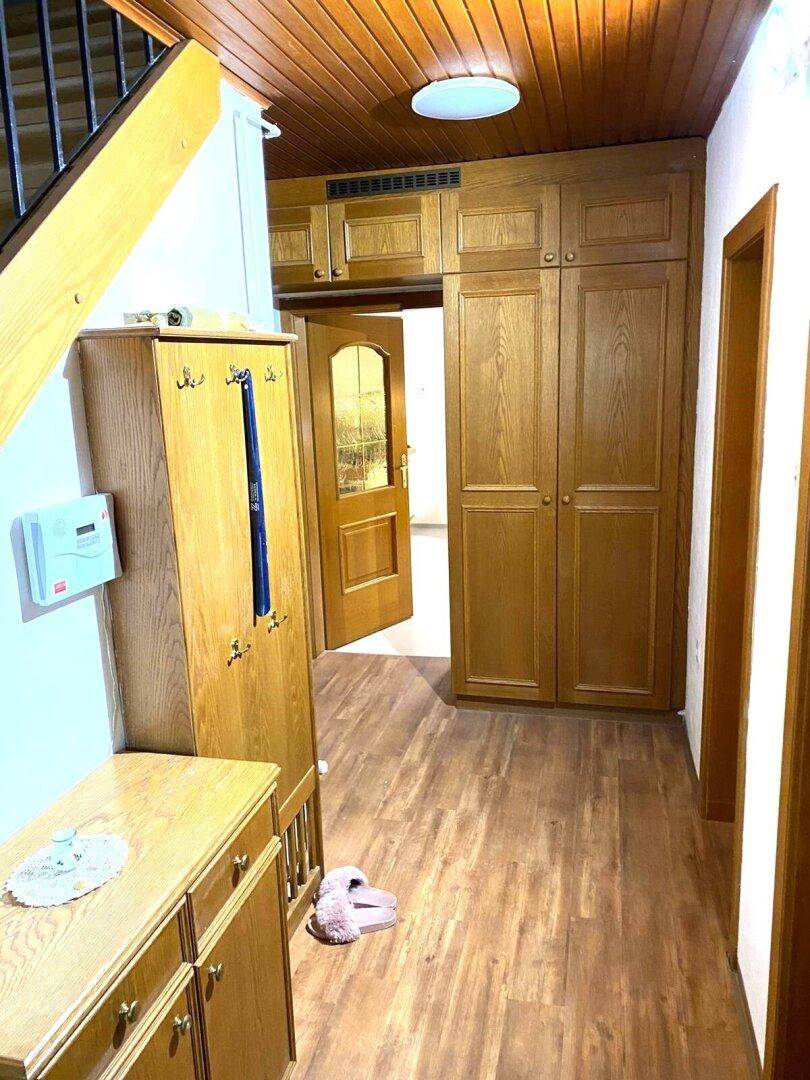 Flur mit Holzvertäfelung an der Decke, Einbauschränken und Holzboden.