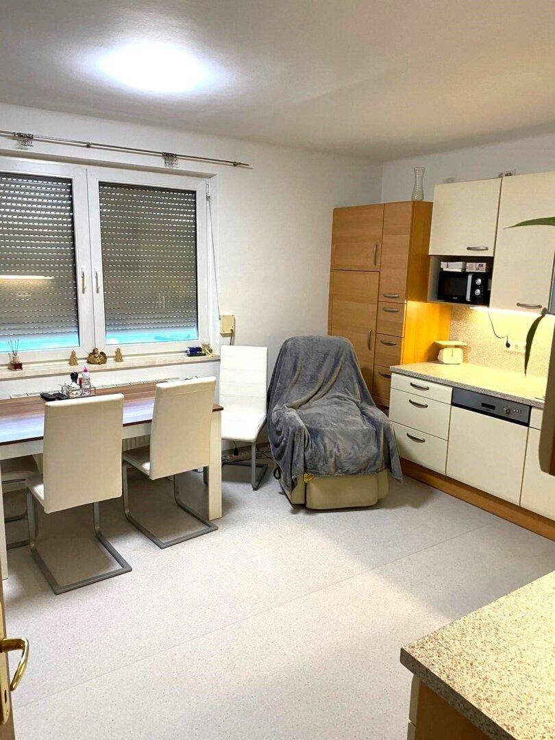 Geräumige Küche mit Essbereich, Einbauschränken und einem Fenster mit Rollläden.