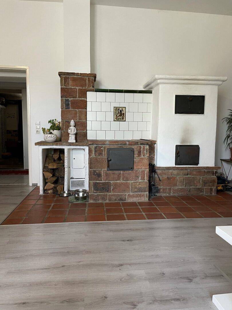Detailansicht eines traditionellen Kachelofens mit Ziegeln und weißer Fliesenverkleidung im Wohnbereich.