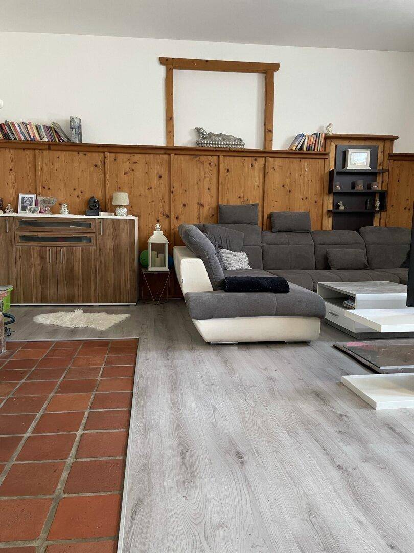 Heller Wohnbereich mit Holzvertäfelung, bequemer Couch und Regalen für Bücher und Dekoration.