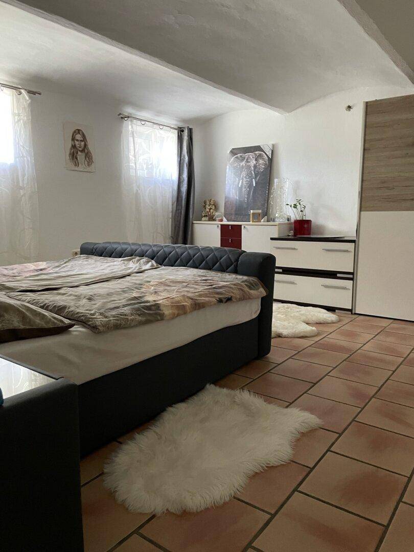 Schlafzimmer mit großem Bett, Terrakottafliesen und viel Tageslicht durch die Fenster.