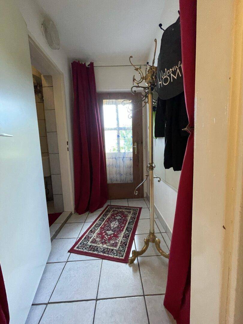 Eingangsbereich mit Fliesenboden, Garderobe und Zugang zur Außentür mit Glasfenstern.
