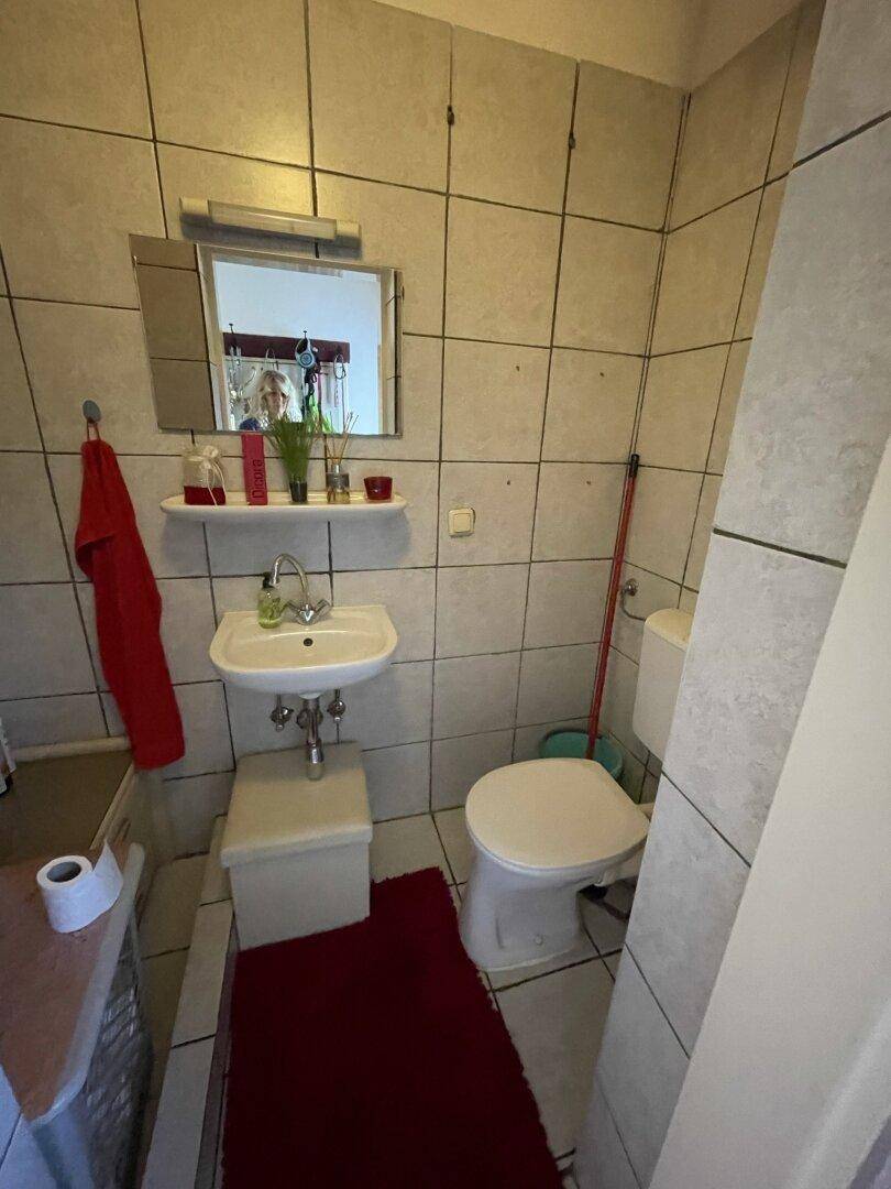 Kleines WC mit Waschbecken, Toilette und Wandfliesen in neutralen Farben.