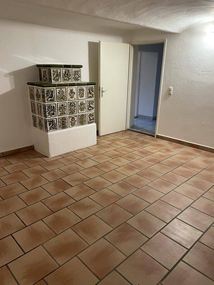 Raum mit gewölbter Decke, Terrakottafliesen und einem verzierten Kachelofen in traditionellem Stil.