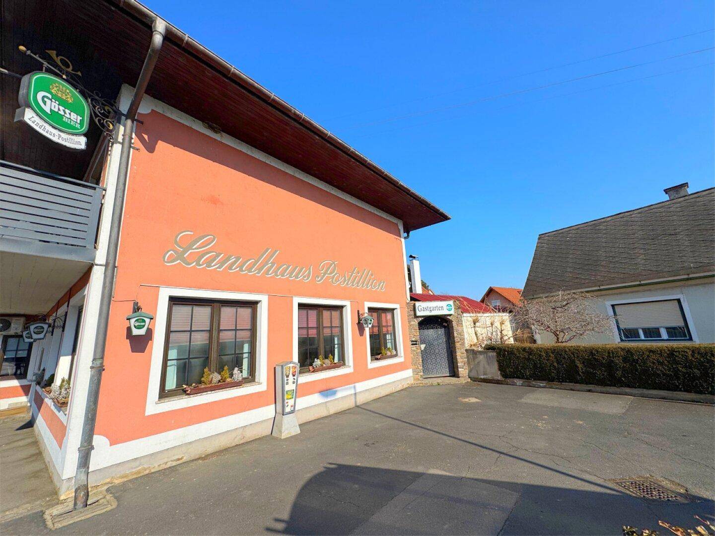 Rückansicht des Landhauses mit Eingang zum Gastgarten und Parkplatzbereich.
