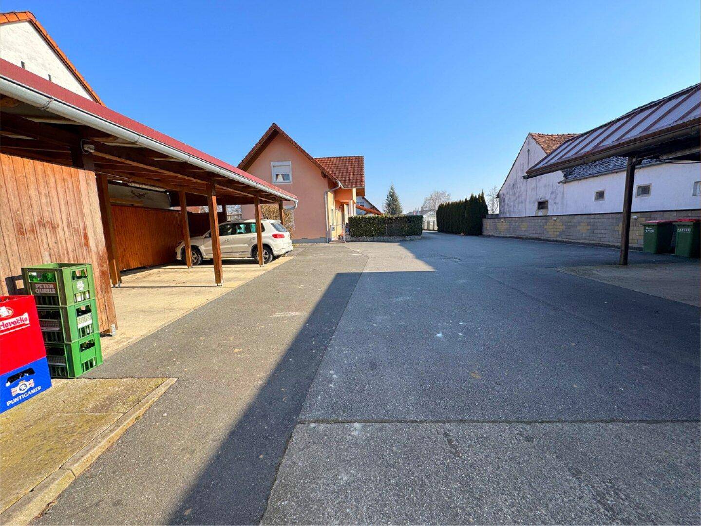 Großer asphaltierter Parkplatzbereich mit Carports und angrenzenden Gebäuden.
