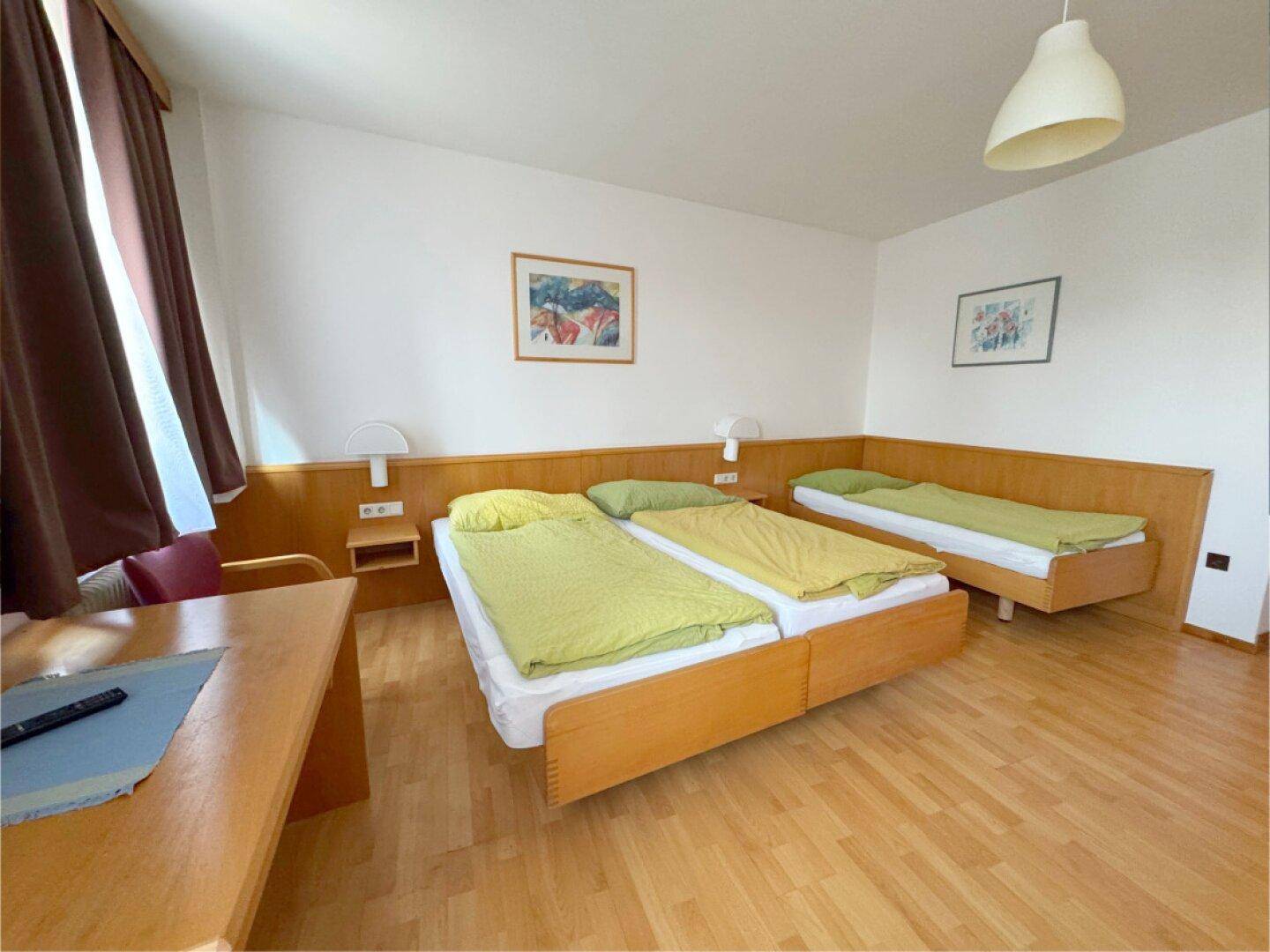 Geräumiges Schlafzimmer mit Holzbetten, Laminatboden und heller Einrichtung.