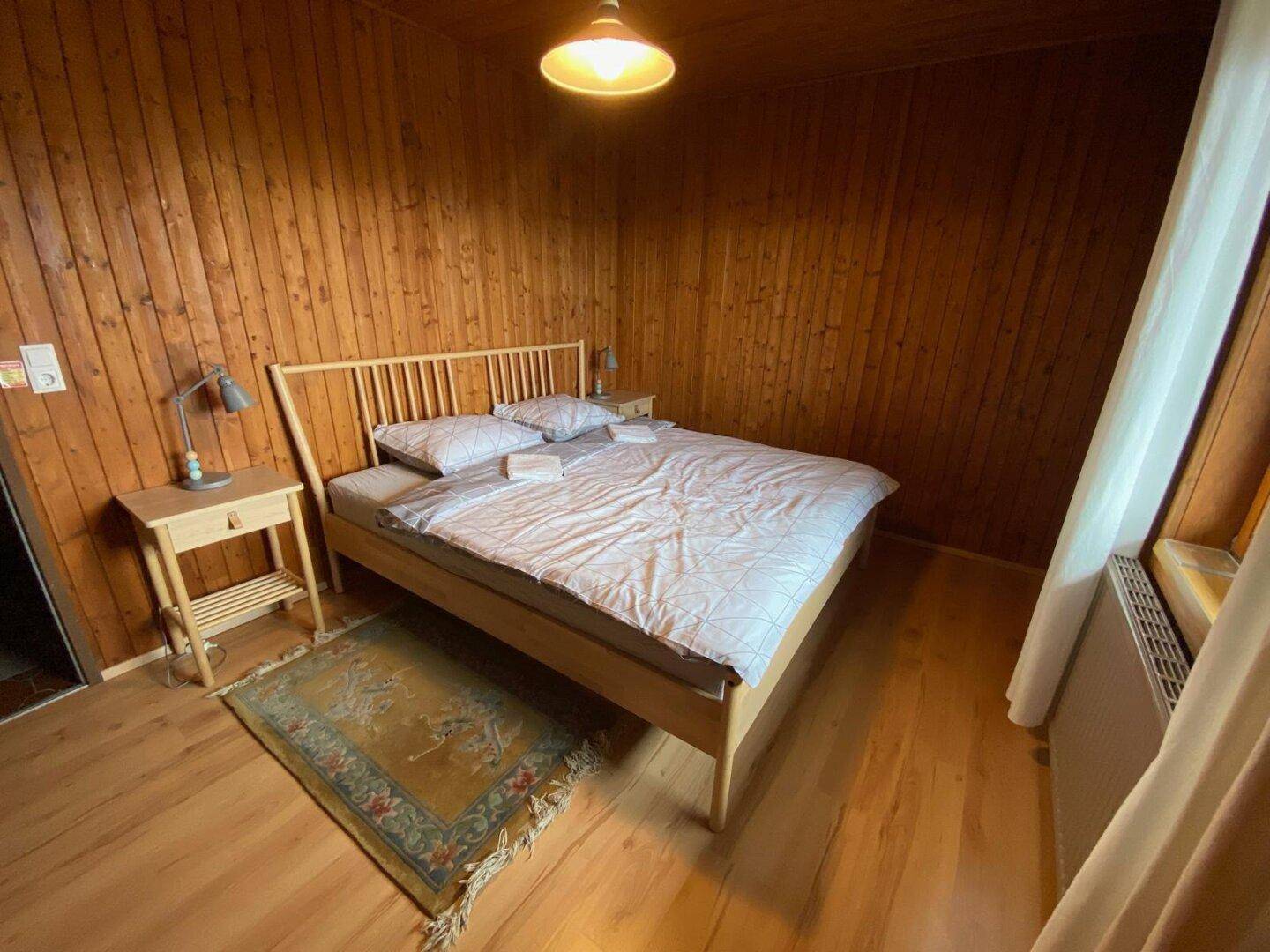 Gemütliches Schlafzimmer mit Holzboden, Holzvertäfelung und einem Doppelbett in traditionellem Stil.