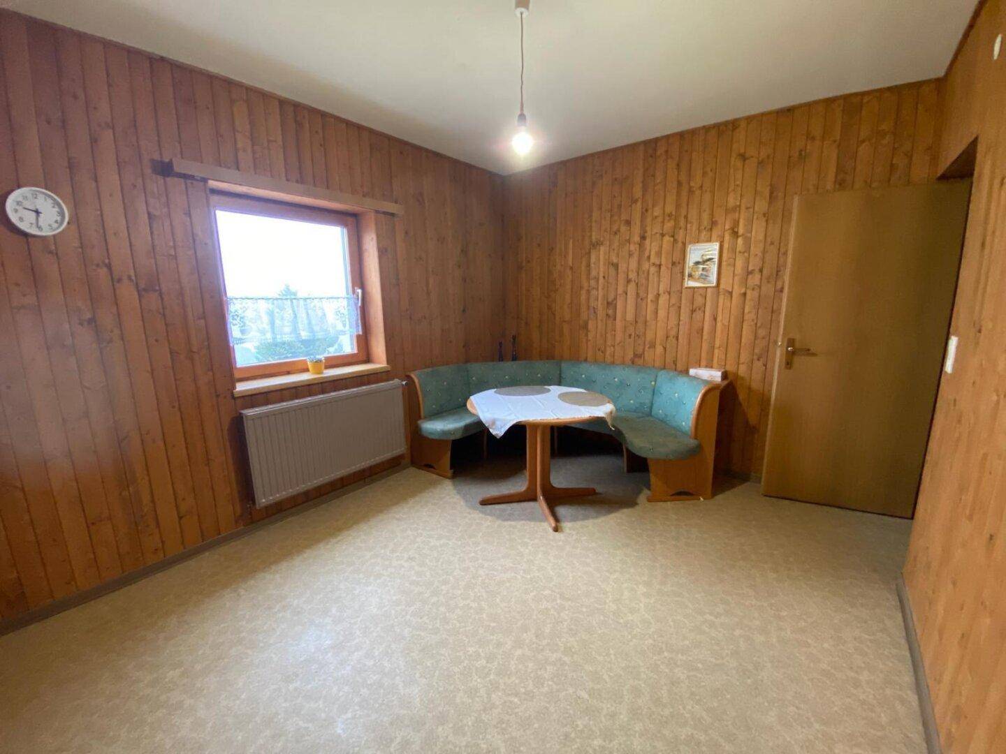 Gemütlicher Essbereich mit Eckbank, Holzwänden und einem Fenster mit Blick ins Grüne.