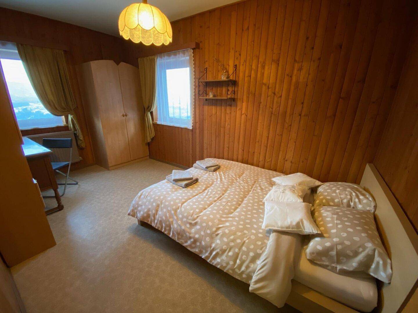 Schlafzimmer mit Vinylboden, Holzvertäfelung und Doppelbett, inklusive Kleiderschrank und Schreibtisch.
