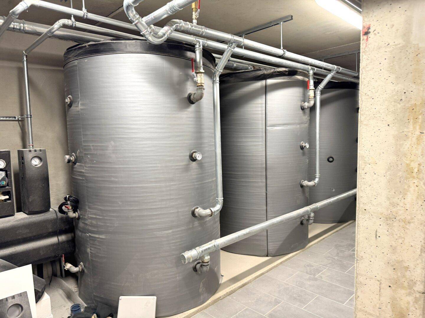 Technikraum mit großen Warmwasserspeichern und sichtbaren Rohrleitungen.
