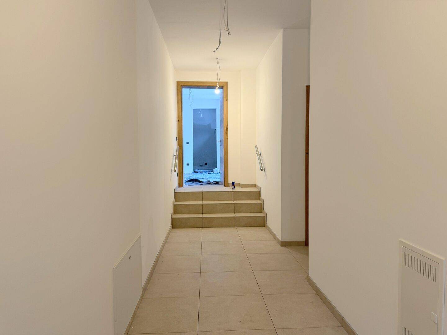 Heller Flur mit Treppenaufgang und Handläufen, noch im Bau.
