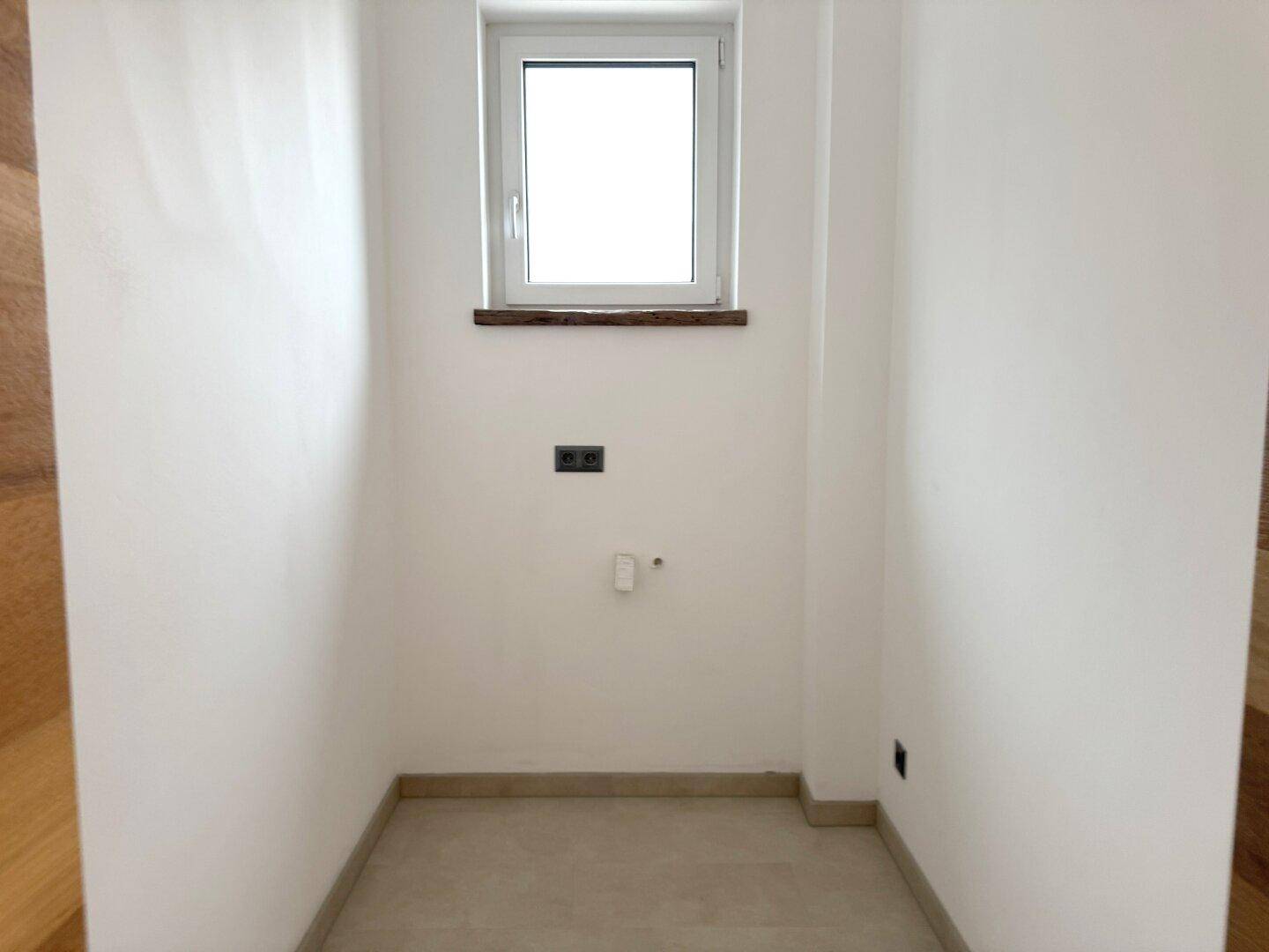 Kleiner Raum mit Fenster und Anschlüssen, möglicherweise für ein Gäste-WC.