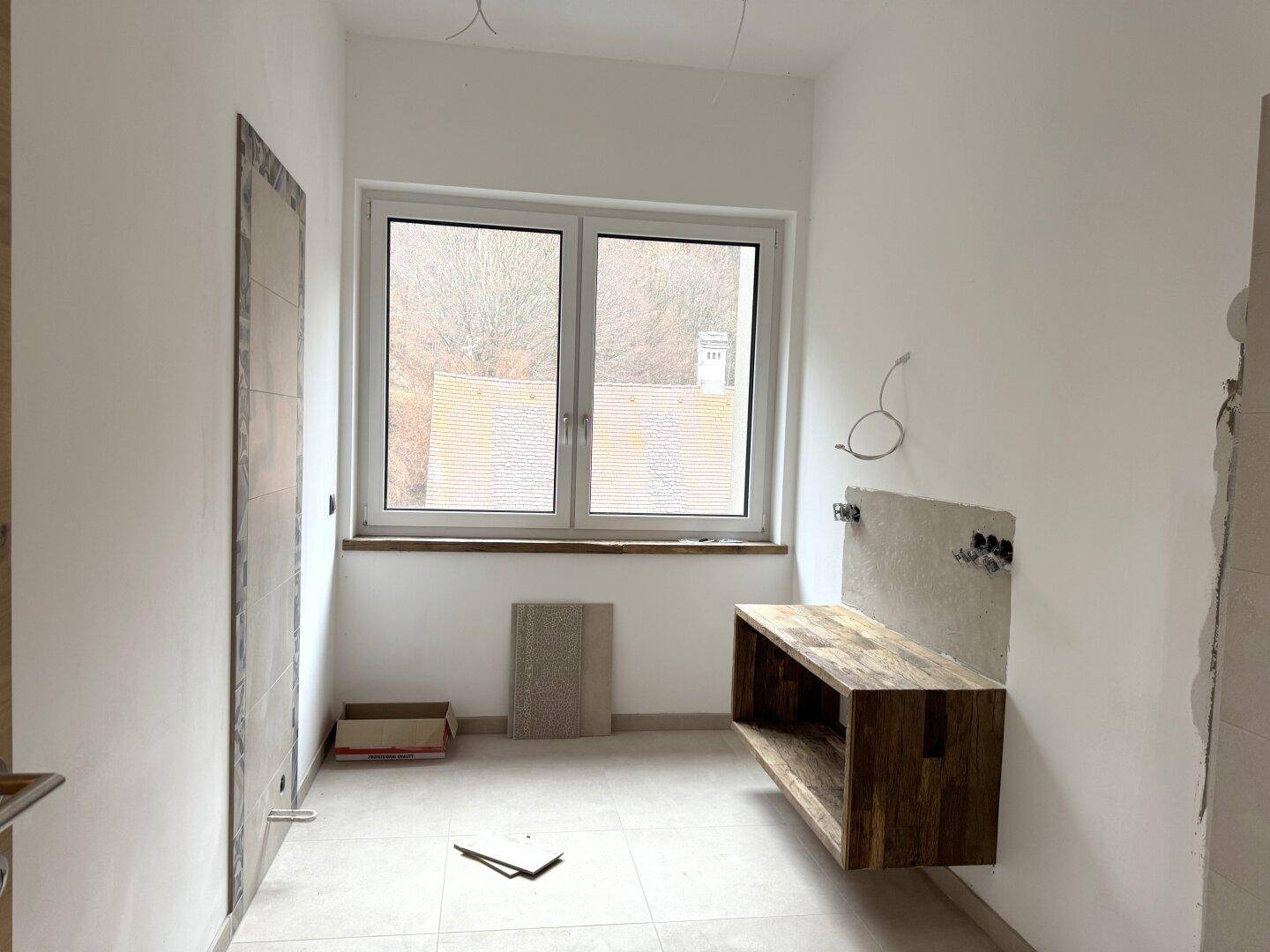 Badezimmer im Bau mit Holzwaschtischunterschrank und großem Fenster.