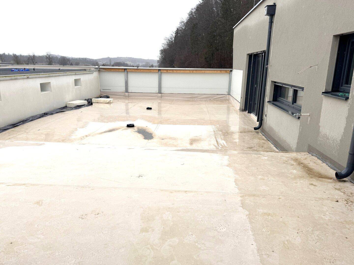 Weitläufige Dachterrasse mit Blick auf die Umgebung und angrenzendes Gebäude.