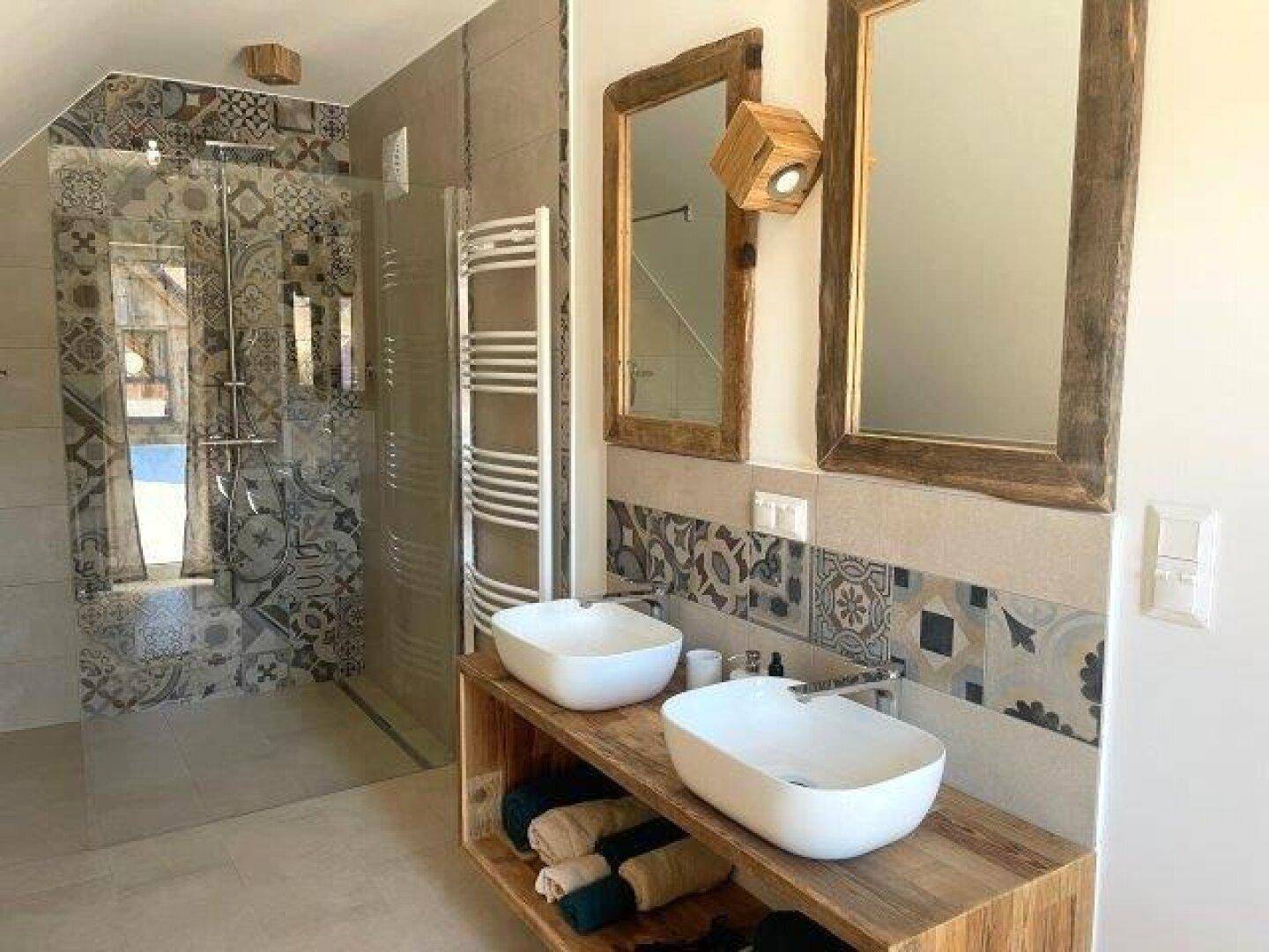 Modernes Badezimmer mit Doppelwaschbecken, begehbarer Dusche und gemusterten Fliesen.