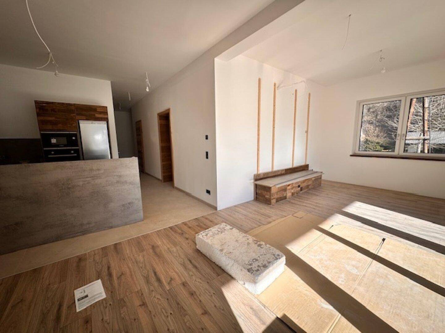Offener Wohnbereich mit Holzboden, eingebauter Bank und viel Tageslicht.