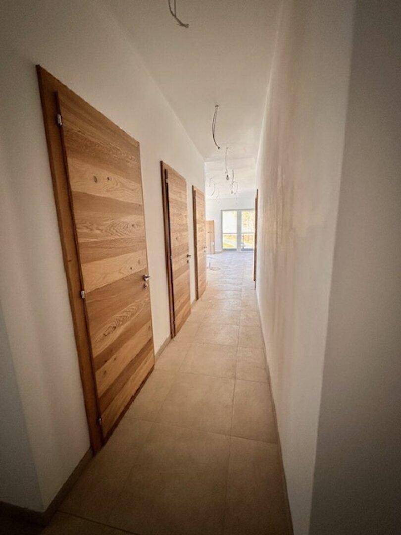 Langer Flur mit Holztüren und Fliesenboden, der zu weiteren Räumen führt.